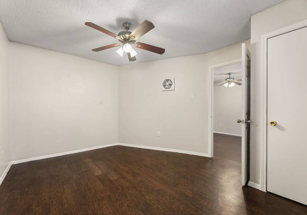 Empty bedroom corner with ceiling fan, vent and doorway to adjoining room at Country Oaks in Weatherford, Texas