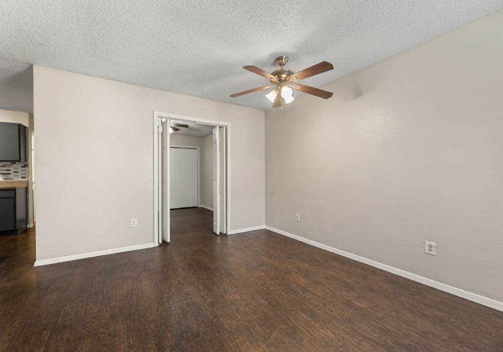 Empty living room with dark plank flooring and doorways to two rooms at Country Oaks in Weatherford, Texas
