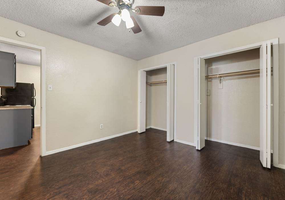 Empty bedroom with two open closets, ceiling fan and view into kitchen at Country Oaks in Weatherford, Texas