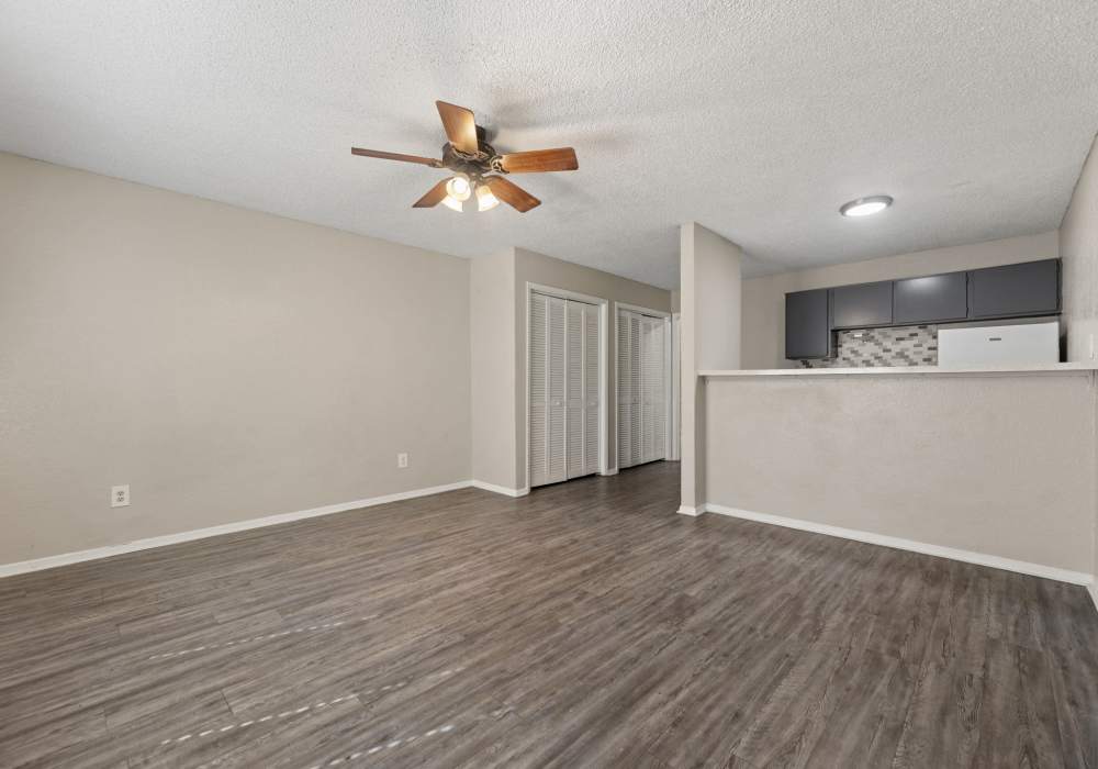 Empty living room with dark plank flooring and doorways to two rooms at Country Oaks in Weatherford, Texas