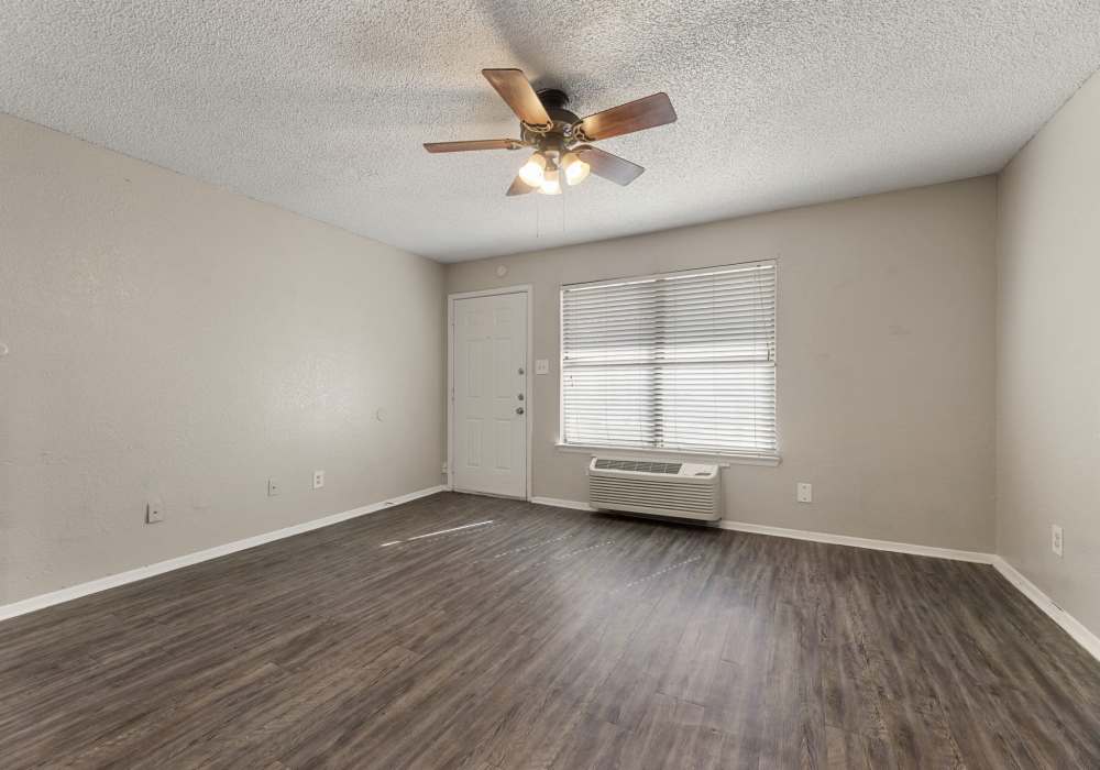 Empty bedroom with dark plank flooring, ceiling fan and hallway to entry at Country Oaks in Weatherford, Texas