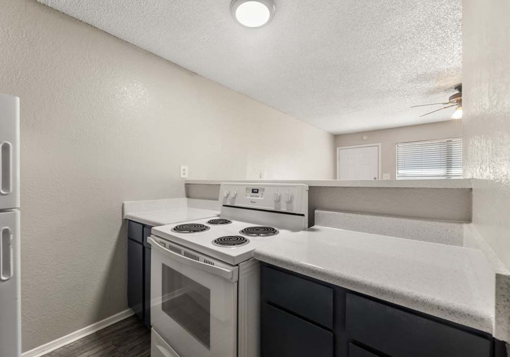 Kitchen corner with gray cabinets, tile backsplash, sink and white refrigerator at Country Oaks in Weatherford, Texas