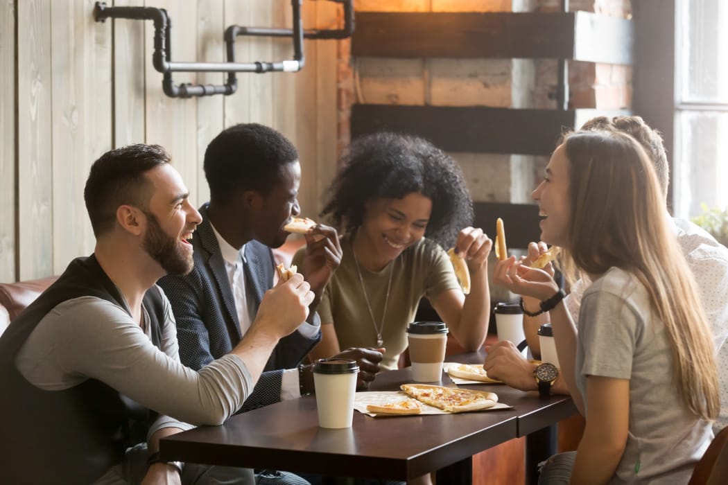 Friends eating pizza in a restaurant near 23Hundred at Ridgeview in Plano, Texas
