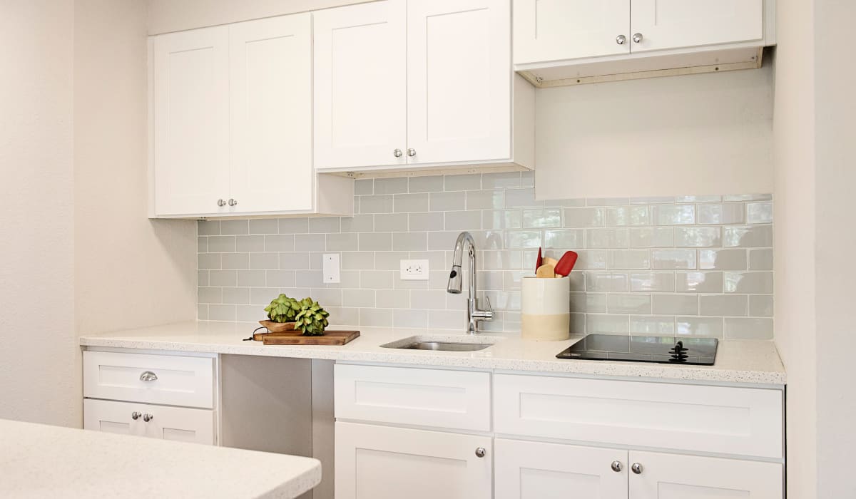 Modern kitchen with subway tile backsplash and white cabinetry and appliances in model home at The Wayland in St Petersburg, Florida