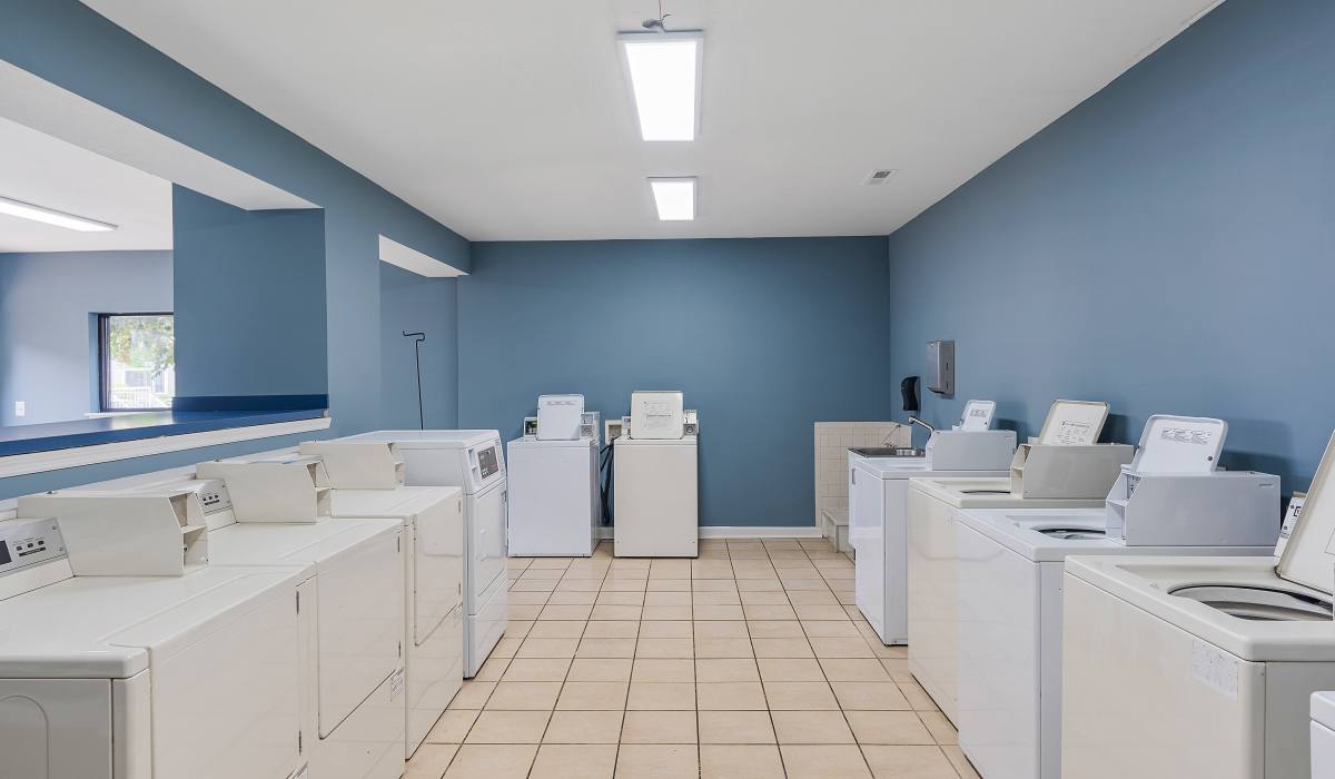 Bright laundry room with multiple white washers and dryers at Burlington Oaks in Burlington, Kentucky