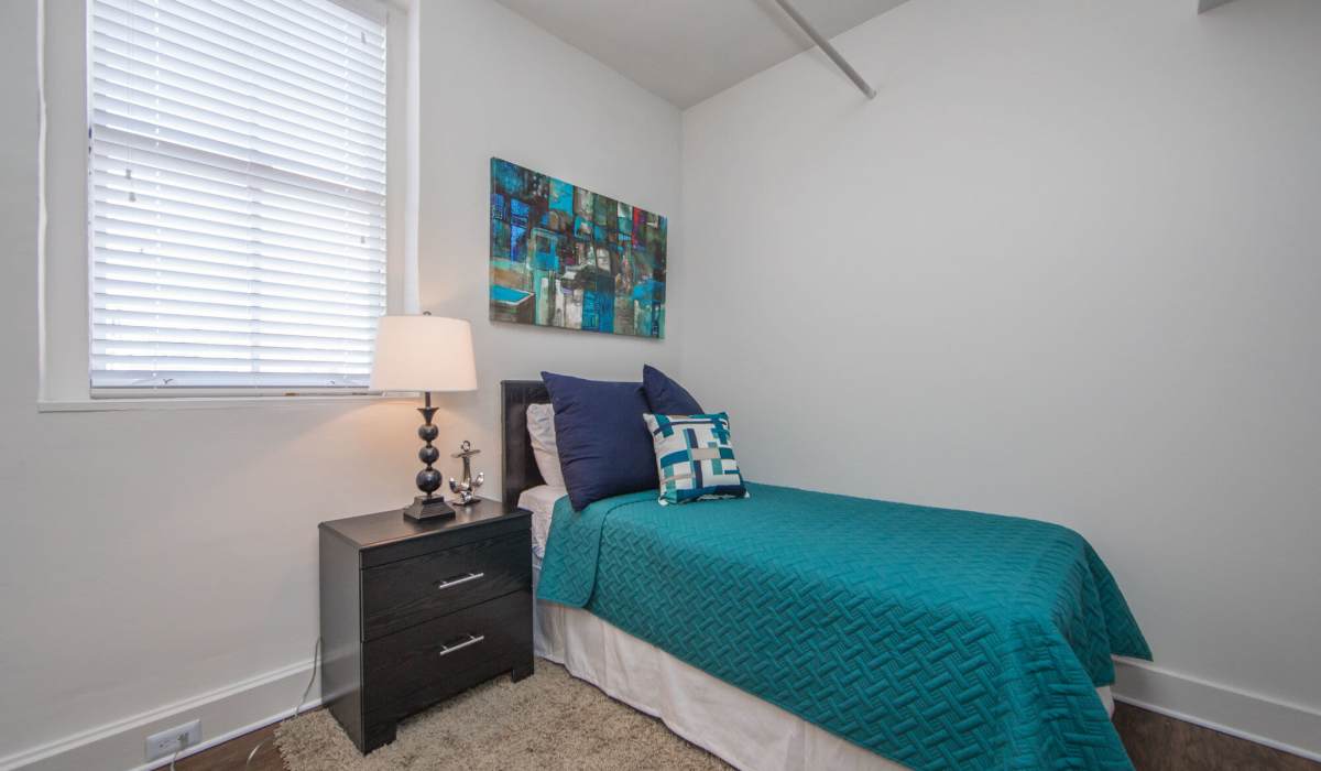 Well-lit apartment bedroom with cozy bed and storage cabinetry at Grace and Monroe Apartments in Richmond, Virginia