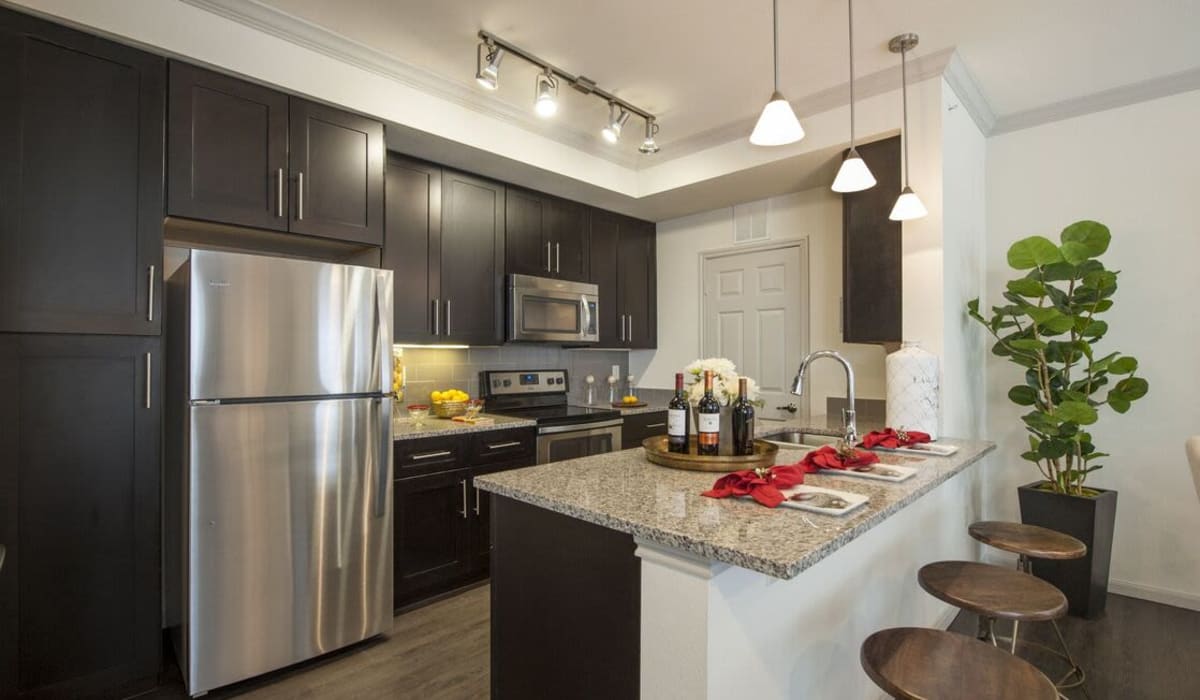 Granite style countertops in a kitchen with black cabinets at The Crossing at Katy Ranch in Katy, Texas