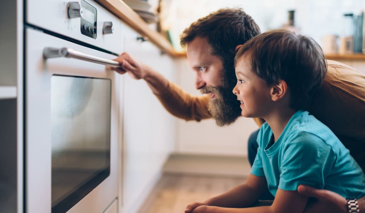 Resident checking oven with his kid at Riverside Apartments in Tempe, Arizona