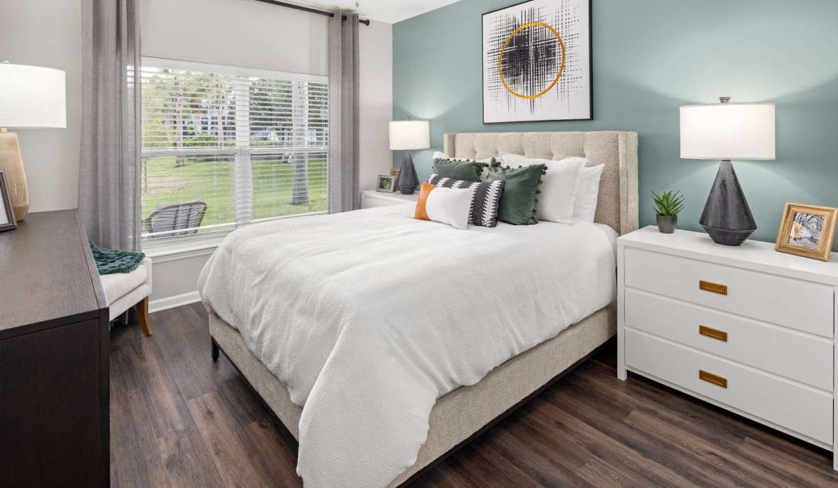 Spacious bedroom with hardwood floors and brightly lit window at Pointe Parc at Avalon in Orlando, Florida