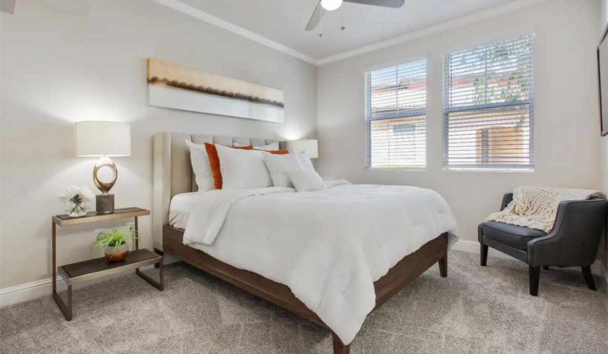 Spacious model bedroom with plush carpeting and a ceiling fan at Villagio Luxury Apartments in Sacramento, California