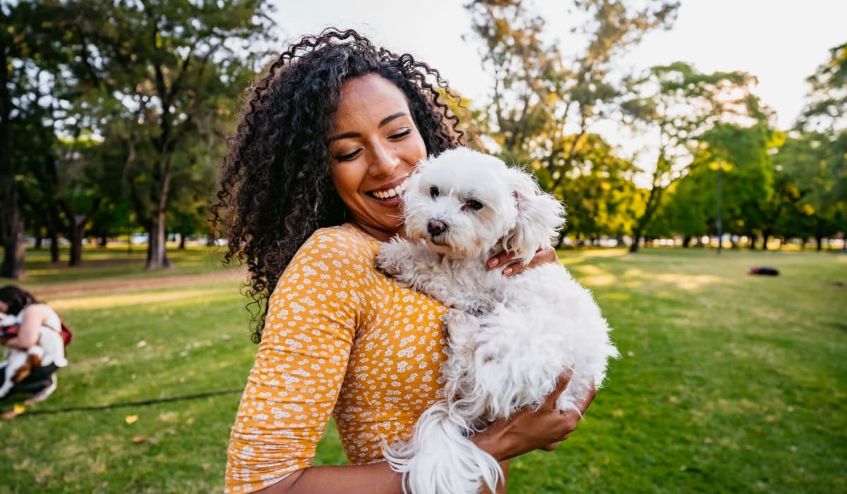 Happy woman holding her dog at park near Lakewood Apartments at Lake Merced in San Francisco, California