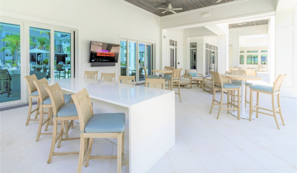 A covered patio with seating and a television for residents at Sentosa Riverview in Riverview, Florida