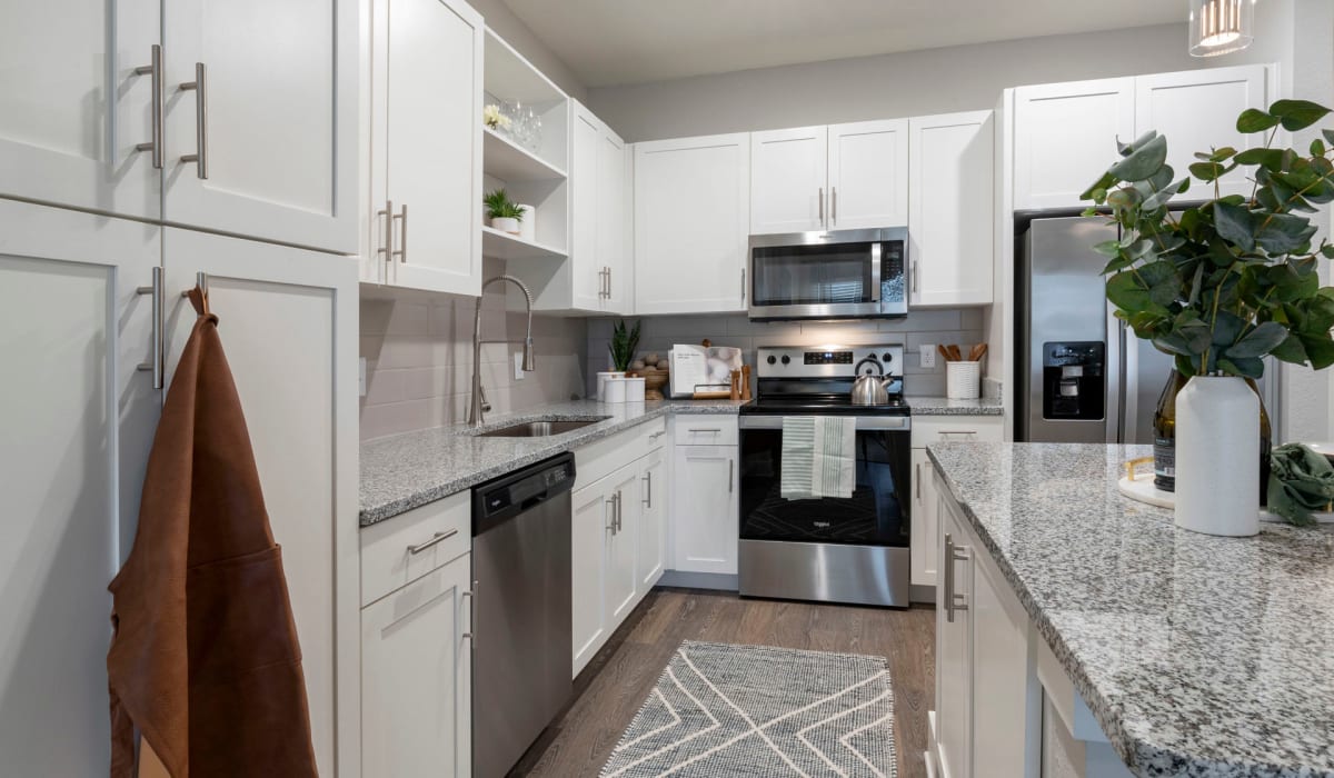White cabinetry and granite countertops in an apartment kitchen at Sentosa Riverview in Riverview, Florida