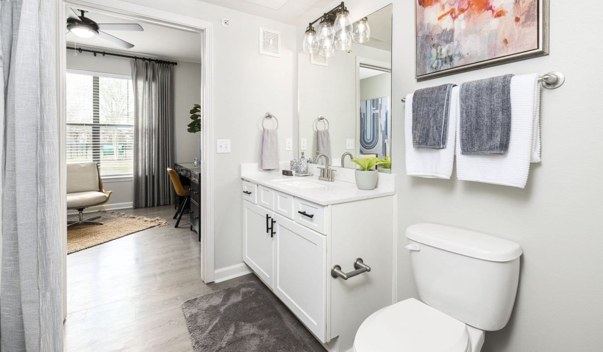 An apartment bathroom with the door open to the living room at Evergreen at Tuscany Villas in Baton Rouge, Louisiana