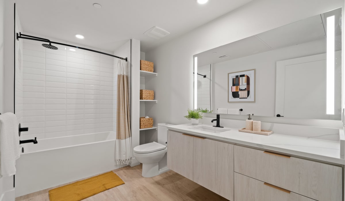 White bathroom with large vanity mirror and cabinets at Aster in Long Beach, California 