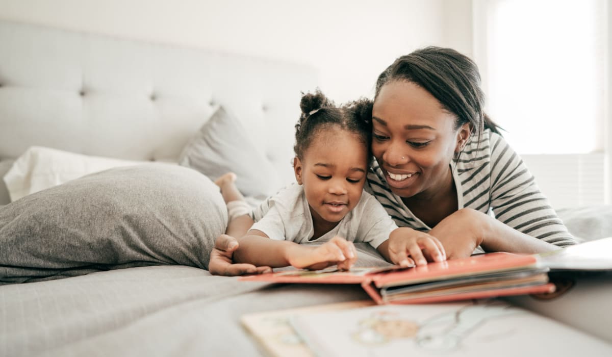 A kid reading story with her mother in bedroom at 1221 Vallejo Apartments in Novato, California