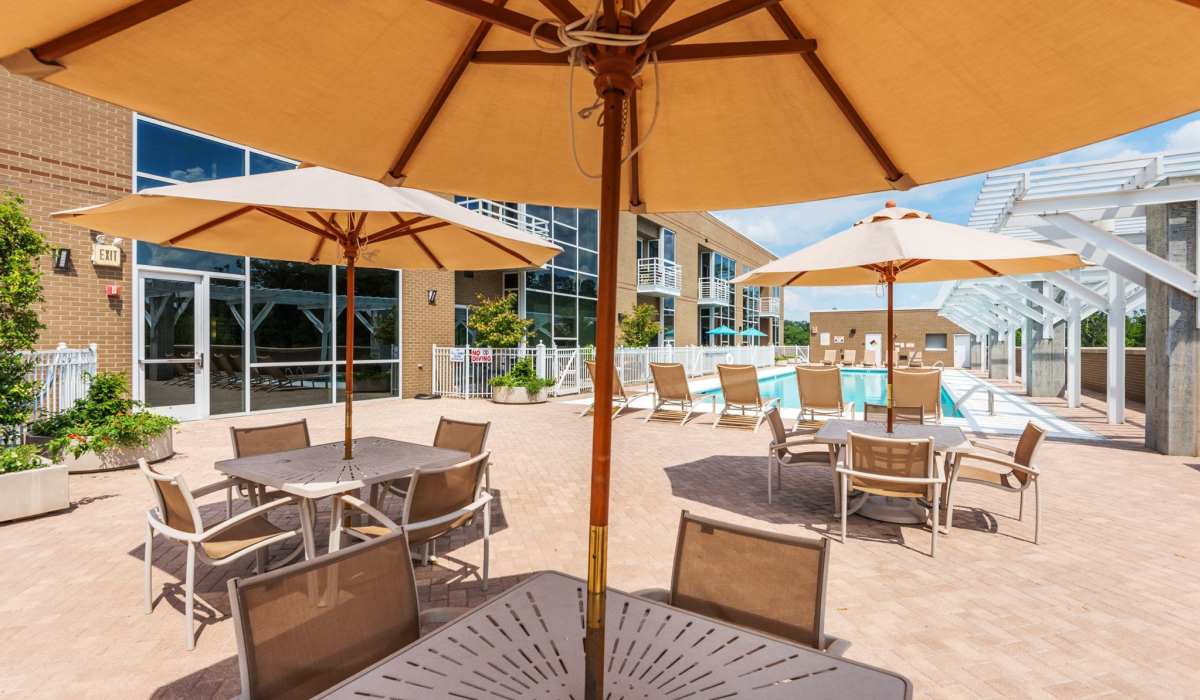 Outdoor tables with umbrellas and chairs beside the swimming pool at Environs Lofts at East 54 in Chapel Hill, North Carolina