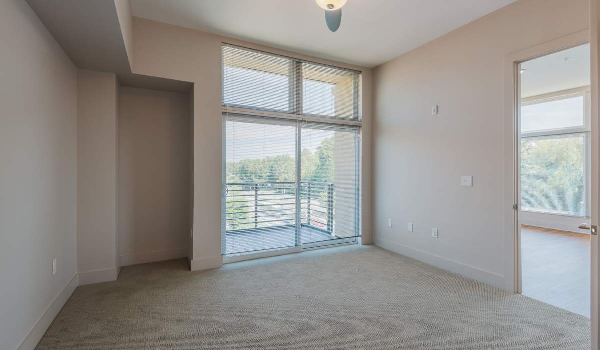 An apartment bedroom with a sliding door to the patio at Environs Lofts at East 54 in Chapel Hill, North Carolina