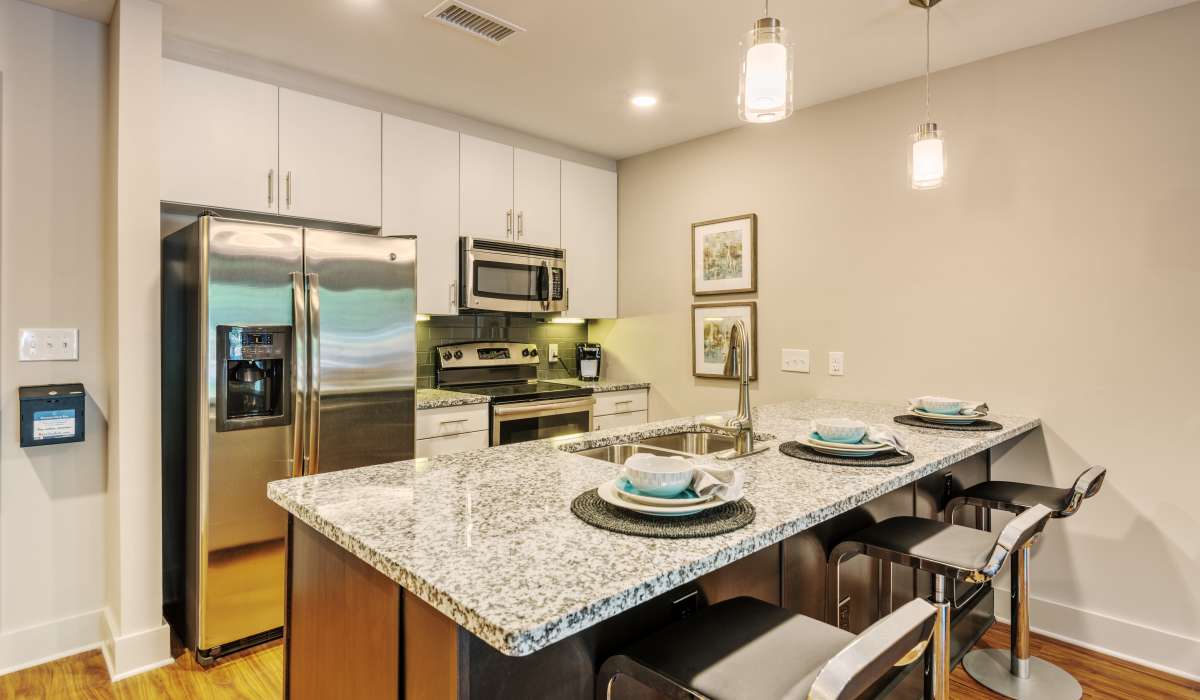 An apartment kitchen with bar seating at an island at Environs Lofts at East 54 in Chapel Hill, North Carolina