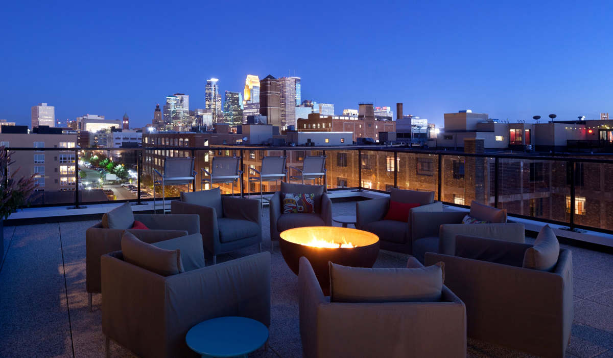 Roof top sitting area with fire pit and nighttime city view at NoLo in Minneapolis, Minnesota