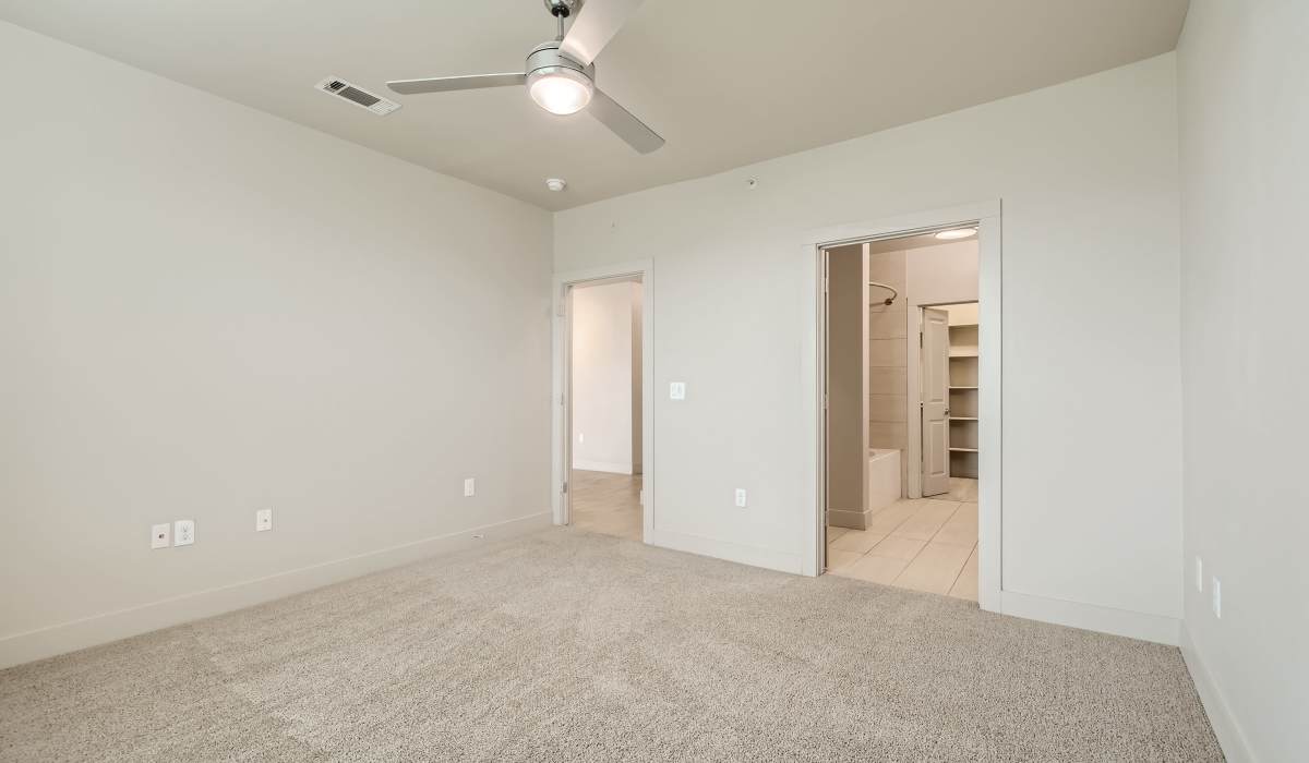 Well-lit and spacious bedroom with attached bathroom and closet at The Lucas Apartments in Dallas, Texas