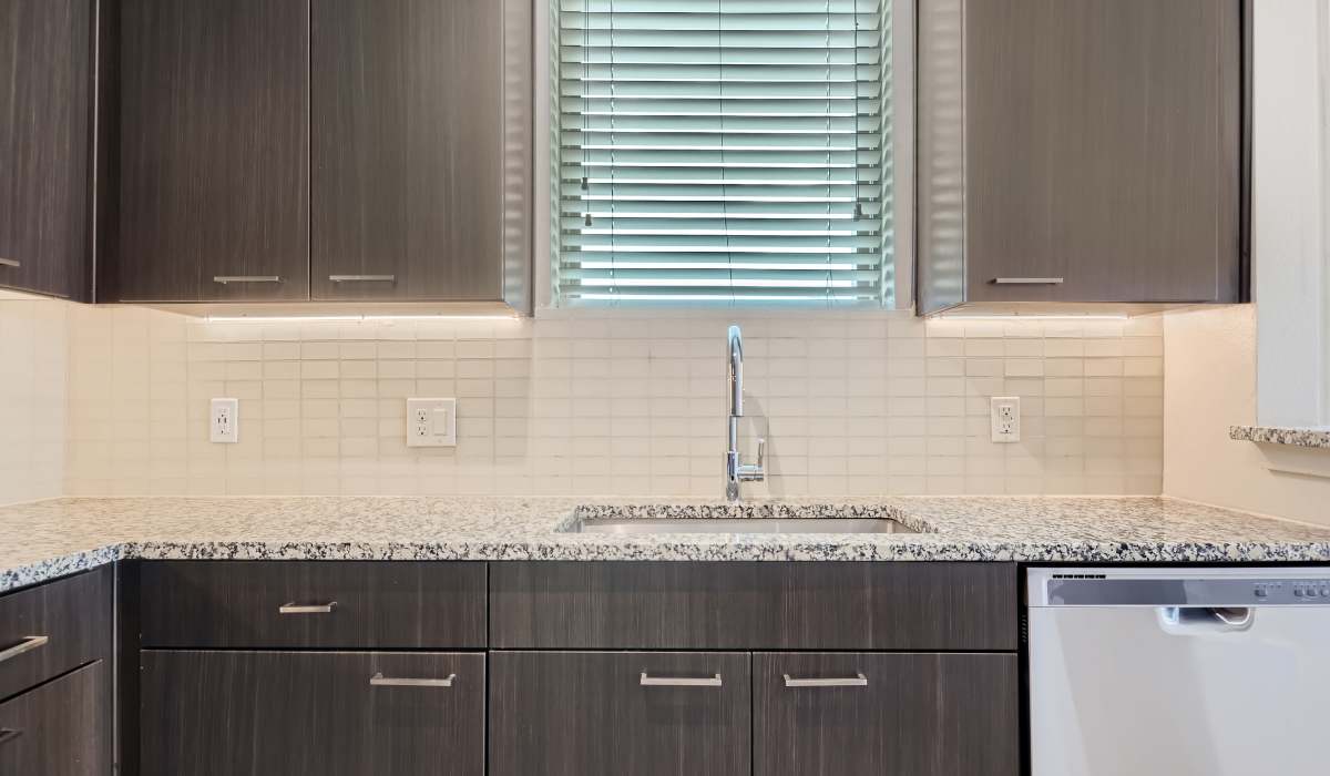 Spacious island kitchen, dishwasher,sink and wood cabinetry at The Lucas Apartments in Dallas, Texas