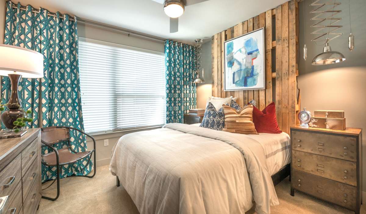 Bedroom with bed, nightstand, and painting on wall at The Lucas Apartments, Dallas, Texas