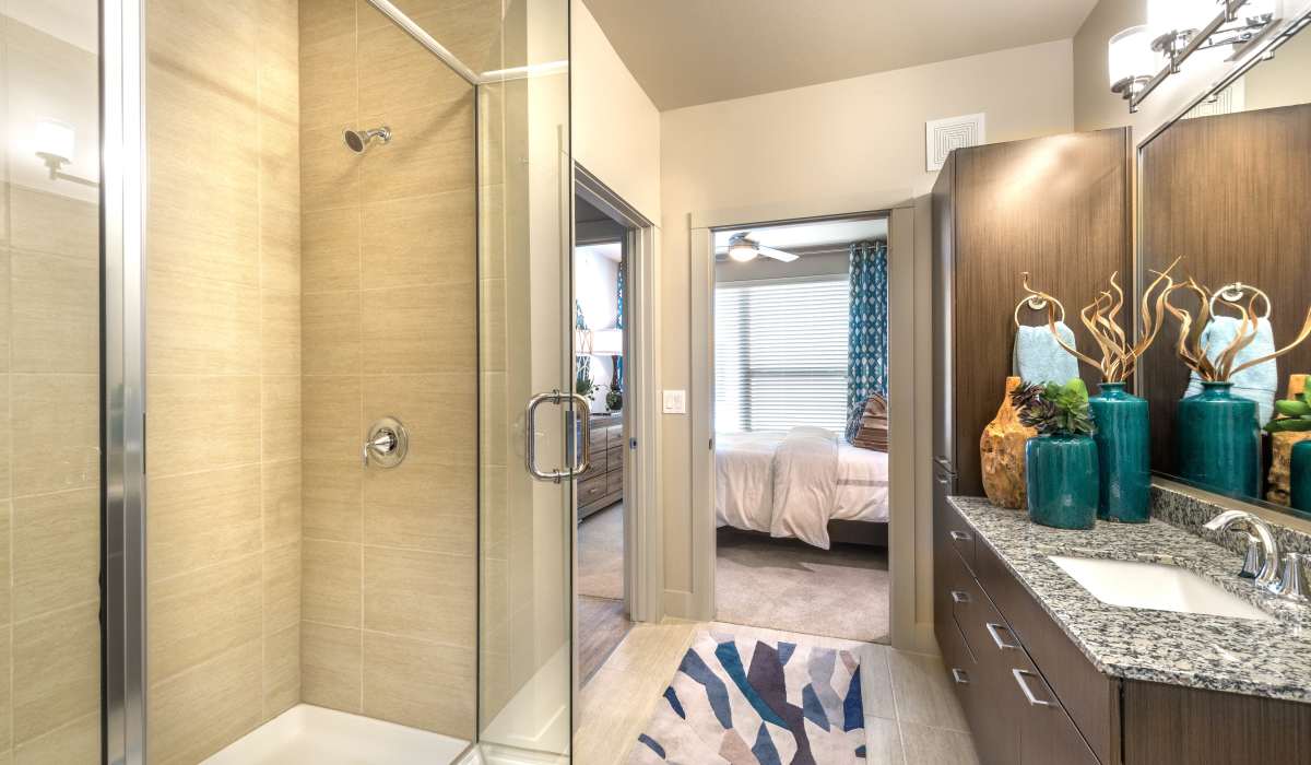 Model bathroom with sink and shower attached to the bedroom at The Lucas Apartments in Dallas, Texas