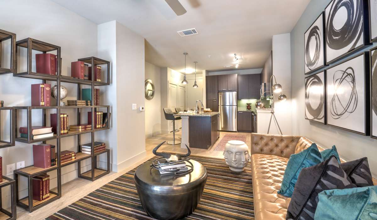 An open and spacious living room with couches adjacent to the kitchen at The Lucas Apartments in Dallas, Texas