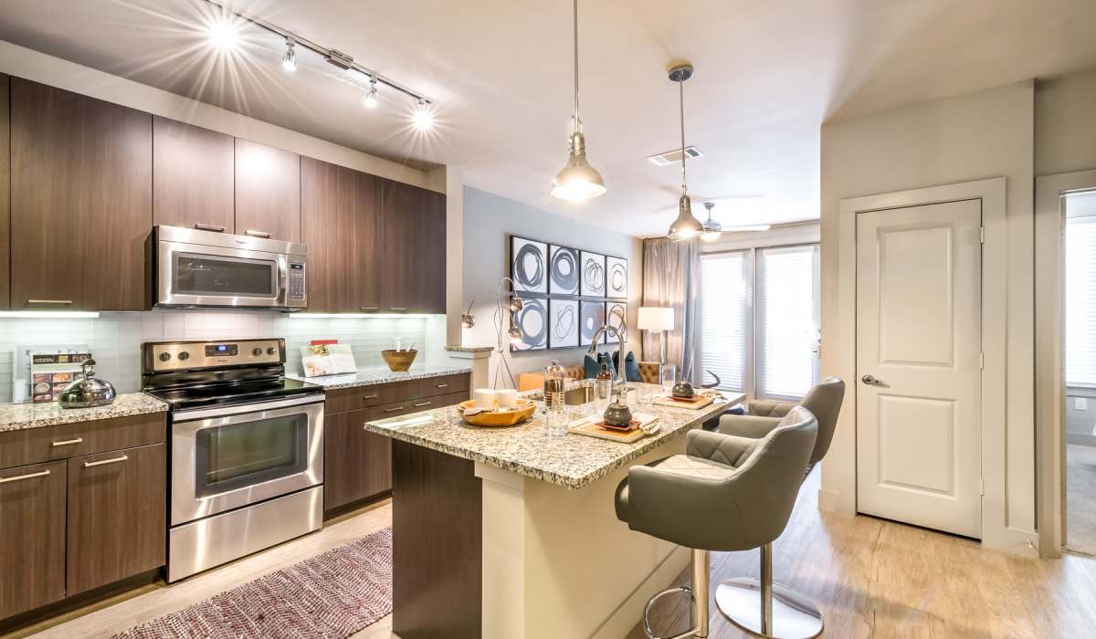 Apartment kitchen with stainless steel appliances and wooden cabinetry at The Lucas Apartments in Dallas, Texas