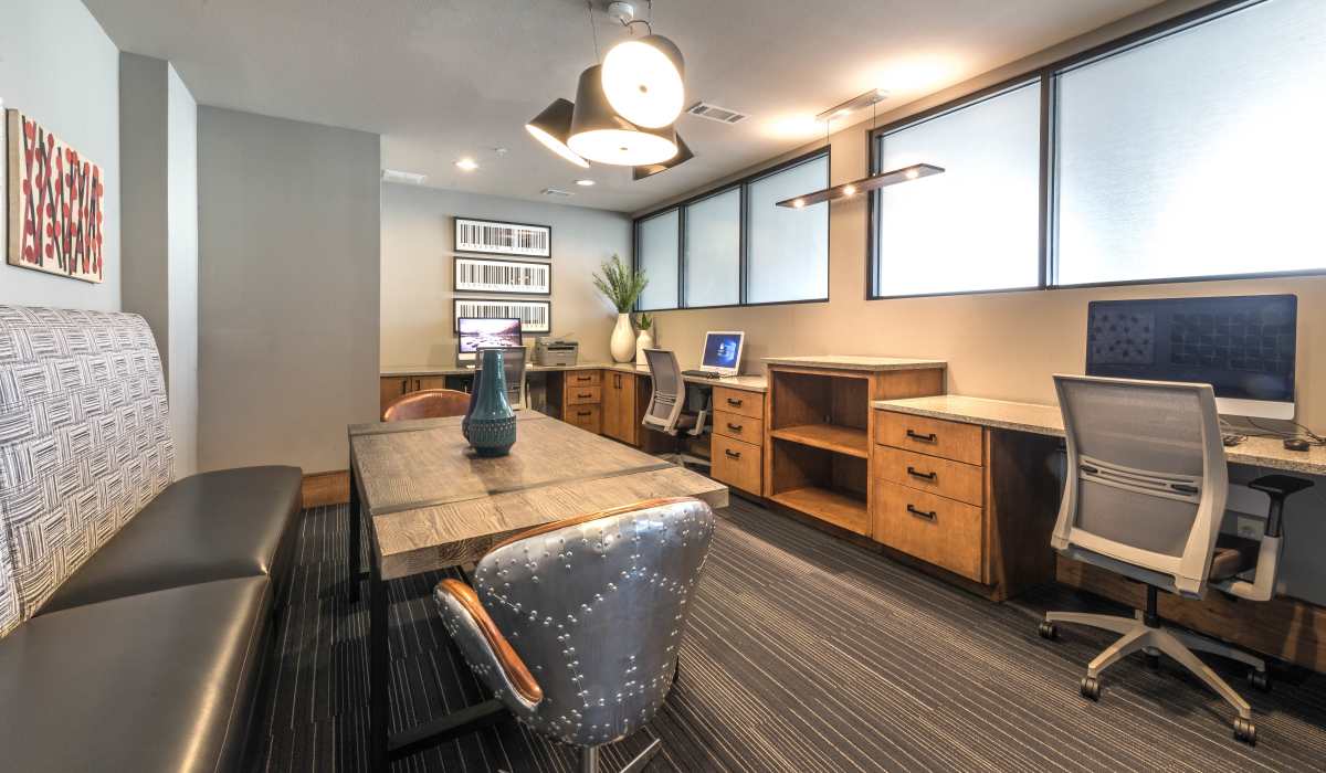 Contemporary office space in a clubhouse, showcasing a desk, chairs, and a computer for efficient work and meetings at The Lucas Apartments in Dallas, Texas