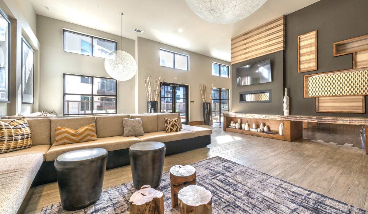A cozy clubhouse living room at the park's edge, featuring comfortable seating and large windows overlooking nature at The Lucas Apartments in Dallas, Texas