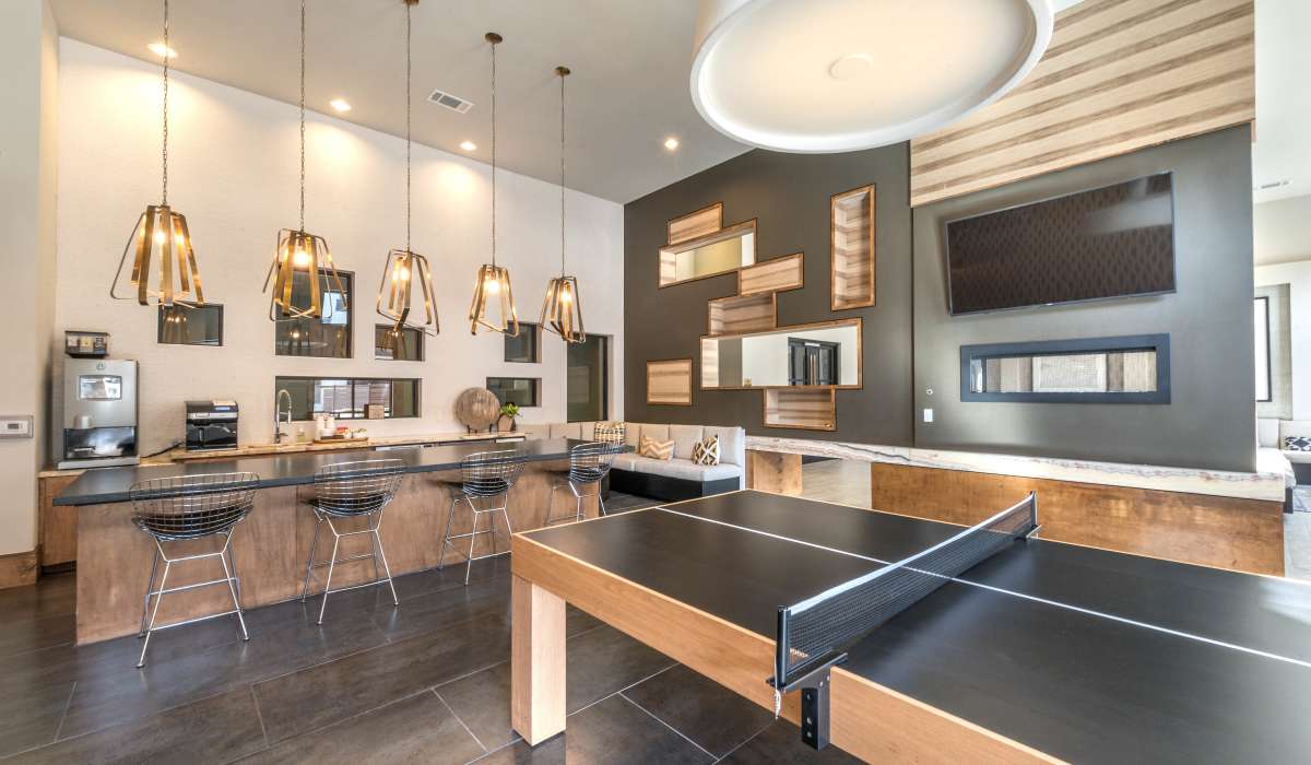 A modern clubhouse featuring a ping pong table and a stylish bar, creating a vibrant social atmosphere at The Lucas Apartments in Dallas, Texas