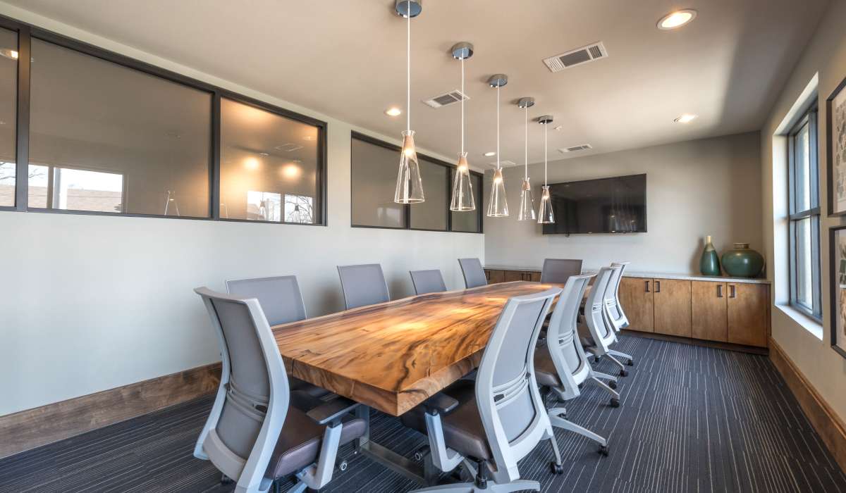 A well-appointed clubhouse conference room showcasing a large table and multiple chairs at The Lucas Apartments in Dallas, Texas