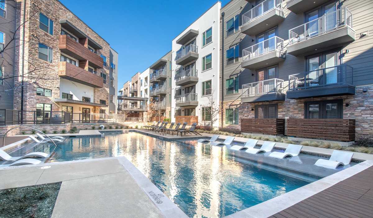 Swimming pool with sitting chairs and table at The Lucas Apartments in Dallas, Texas