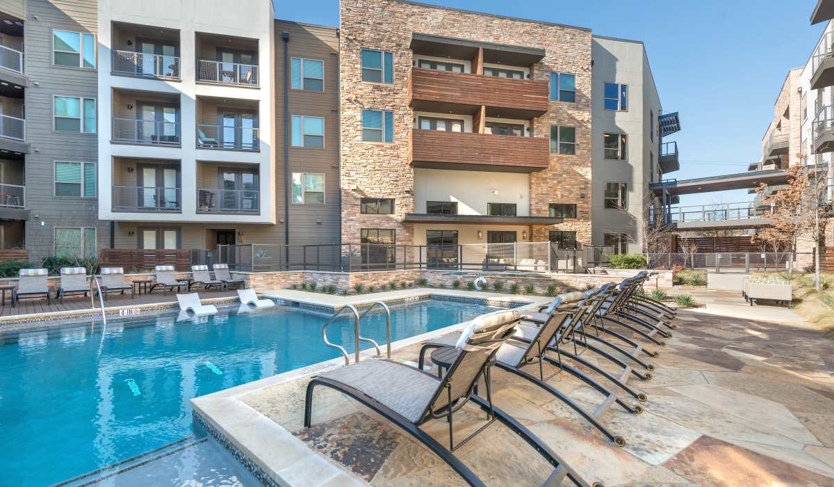 Swimming pool with community building view at The Lucas Apartments in Dallas, Texas