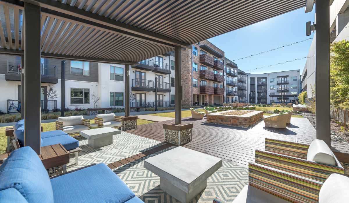 Refreshing sitting area by the pool with an shade at The Lucas Apartments in Dallas, Texas