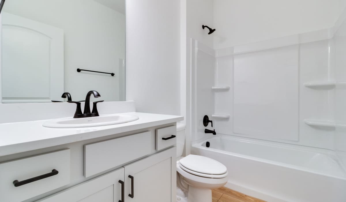 Bathroom with white cabinetry in a model home at Cottages at Sugar Mill Pond in Youngsville, Louisiana
