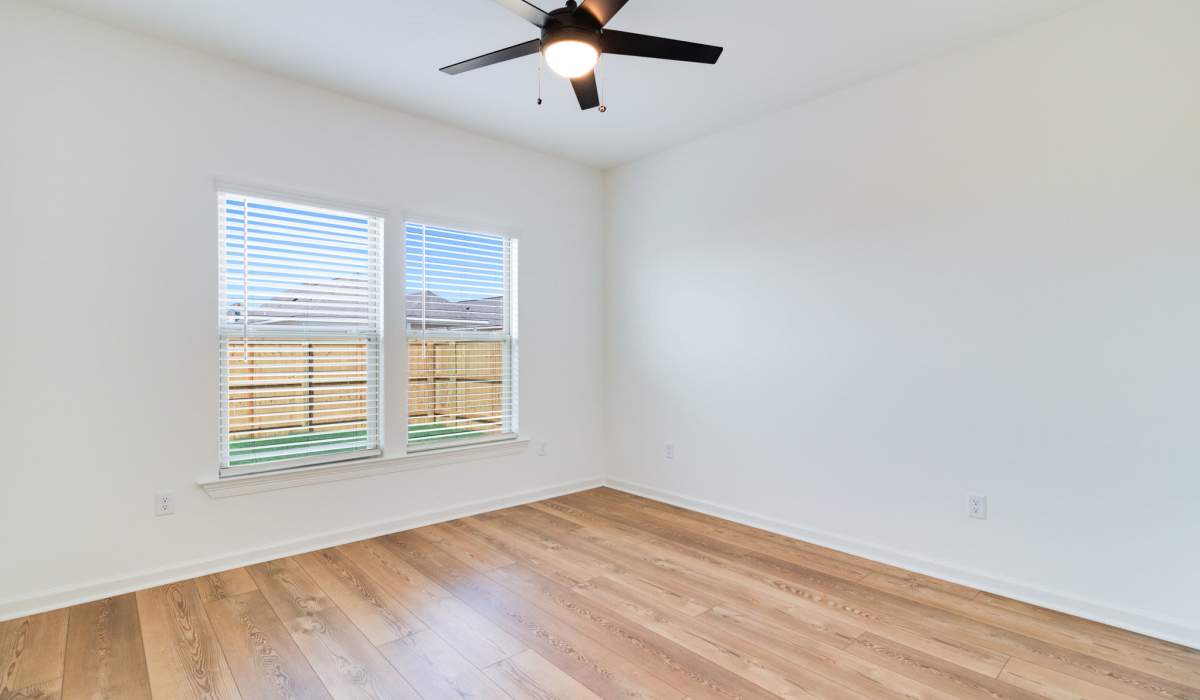 Living room with wood floors and ceiling fan in a model home at Cottages at Sugar Mill Pond in Youngsville, Louisiana