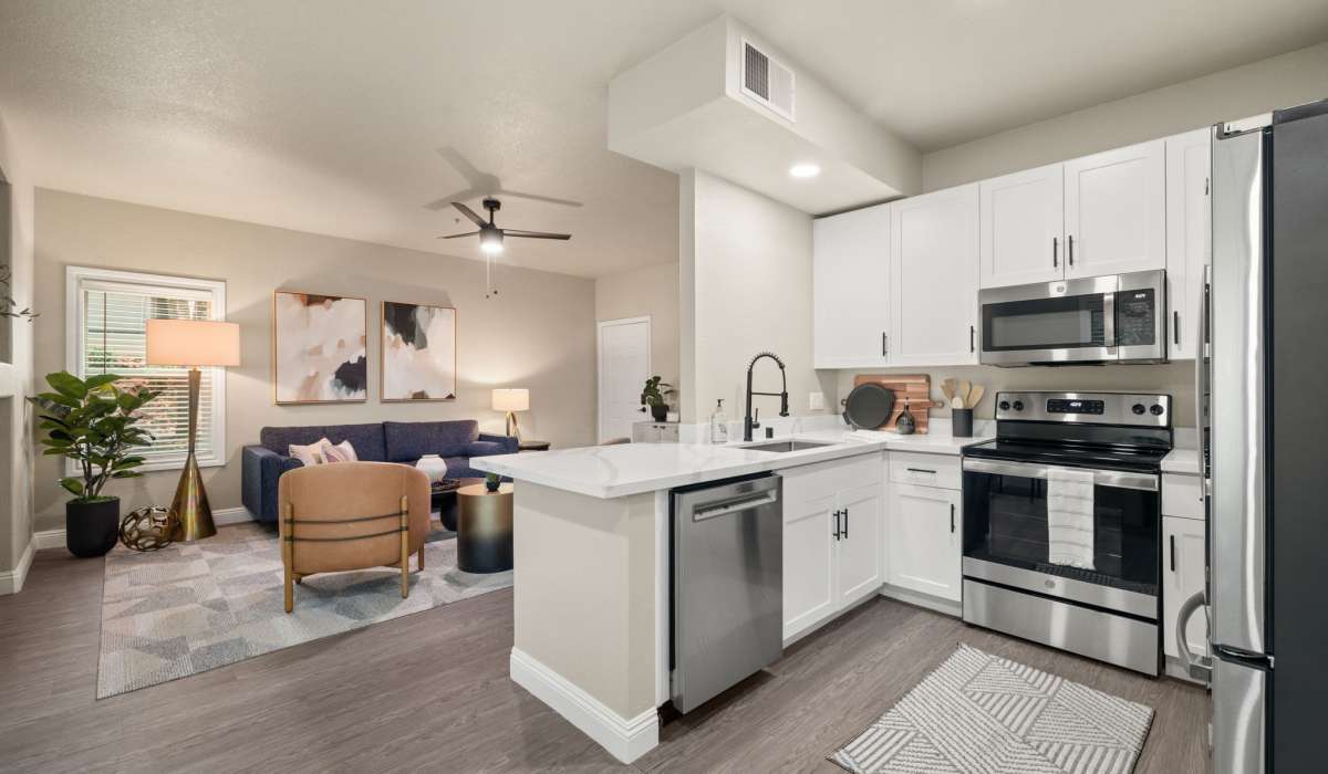 A modern kitchen featuring stainless steel appliances, seamlessly connected to a cozy living room area at The Preserve at Creekside in Roseville, California  