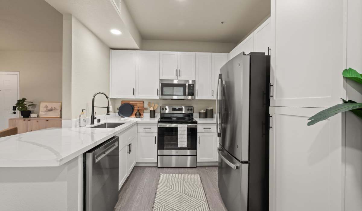 A stylish kitchen with stainless steel appliances, adjacent to a comfortable living room space at The Preserve at Creekside in Roseville, California  
