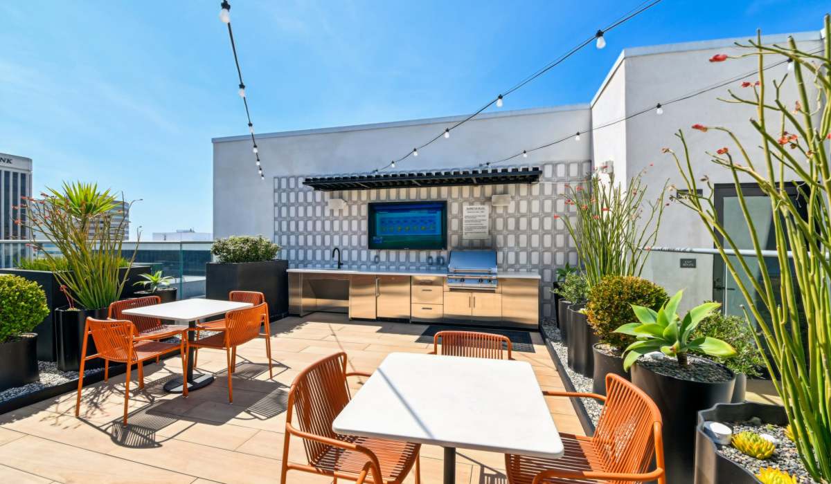 Outdoor barbecue area with sink and chairs and tables at Aster in Long Beach, California
