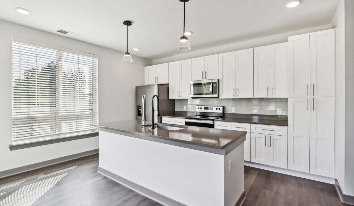 Kitchen with island and hanging light at The Apartments at 1st on Main in Carmel, Indiana