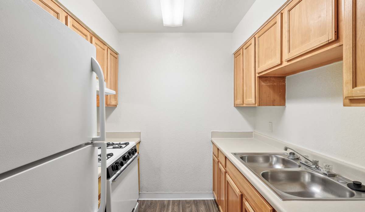 Cozy apartment kitchen with wooden storage units and trendy appliances at Bella Vista Apartments in Phoenix,Arizona