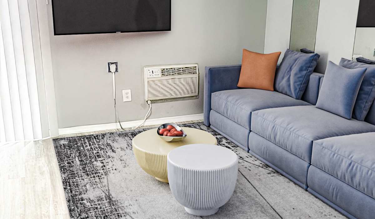 A living room scene with a comfortable couch, a table in front, and a television mounted on the wall at Cliffside at Mountain Park in El Paso, Texas