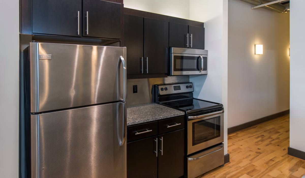Modern kitchen with refrigerator and dark cabinetry at Scotts Edge in Richmond, Virginia