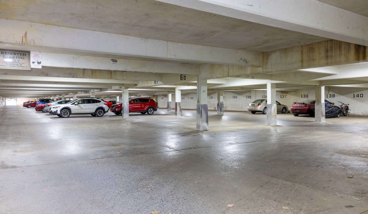 Covered parking garage with multiple parked vehicles in marked spaces at Rugby Square Apartments in Syracuse, New York