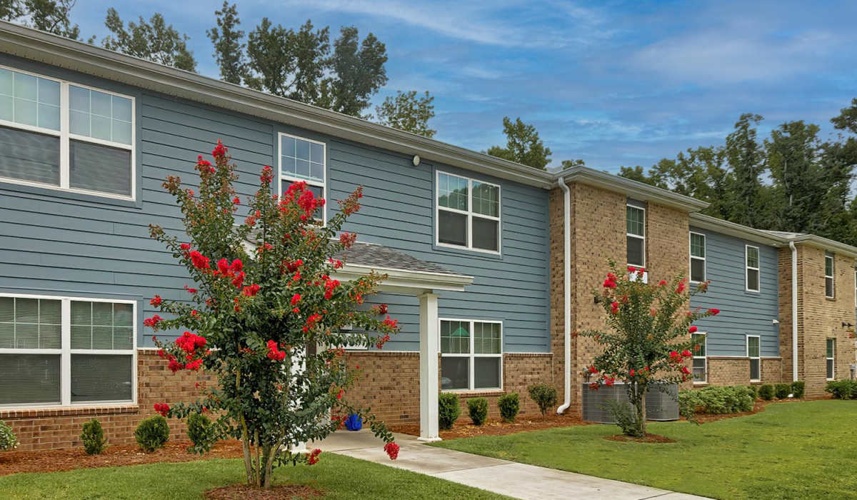 Apartment building exterior with landscaped flowers and greenery at Lowcountry Crossing in Denmark, South Carolina
