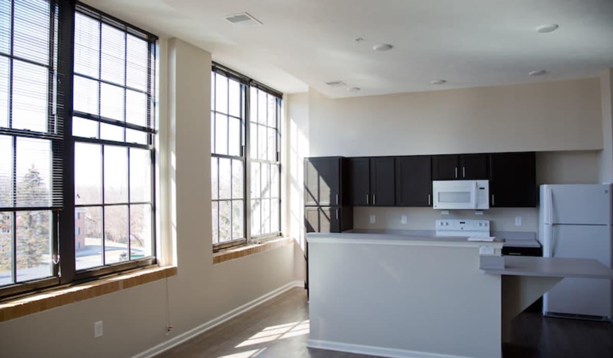 Bright open layout with large windows, modern kitchen, dark cabinetry, and wood-style flooring at Portland School in Portland, Michigan