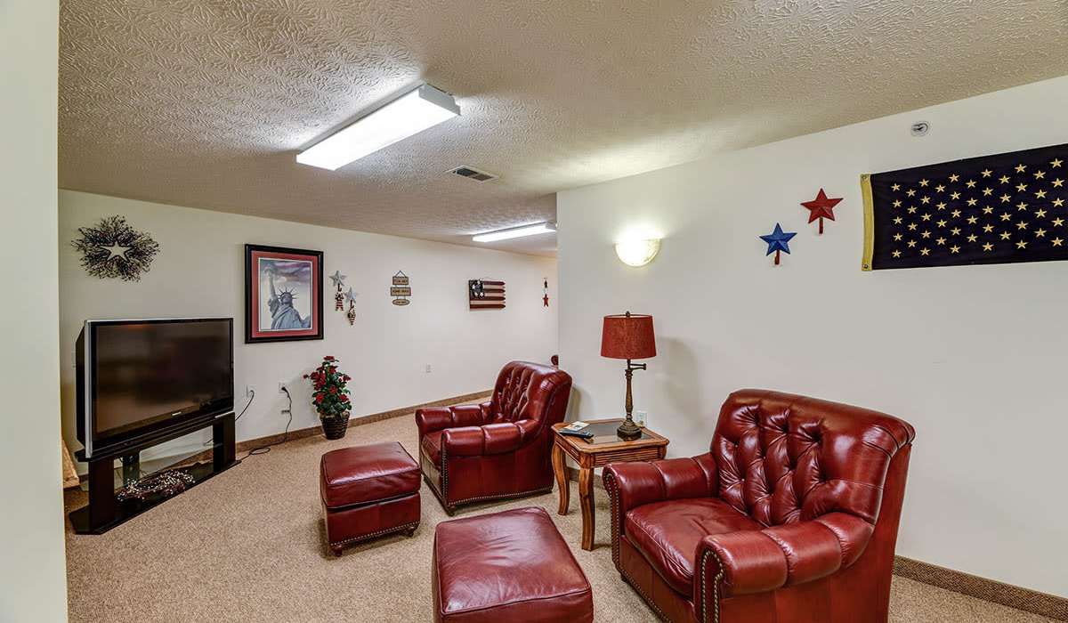 Cozy living room with red leather chairs at Beaumont Greene Senior Living in Athens, Ohio